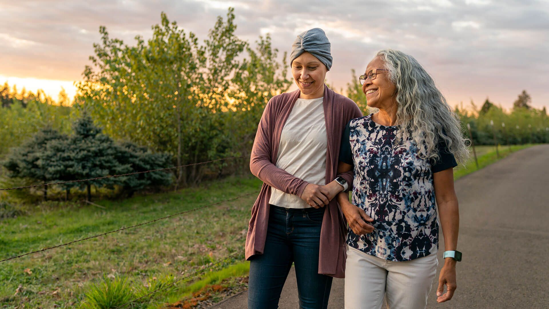 Young woman with cancer walks in a park with her mother