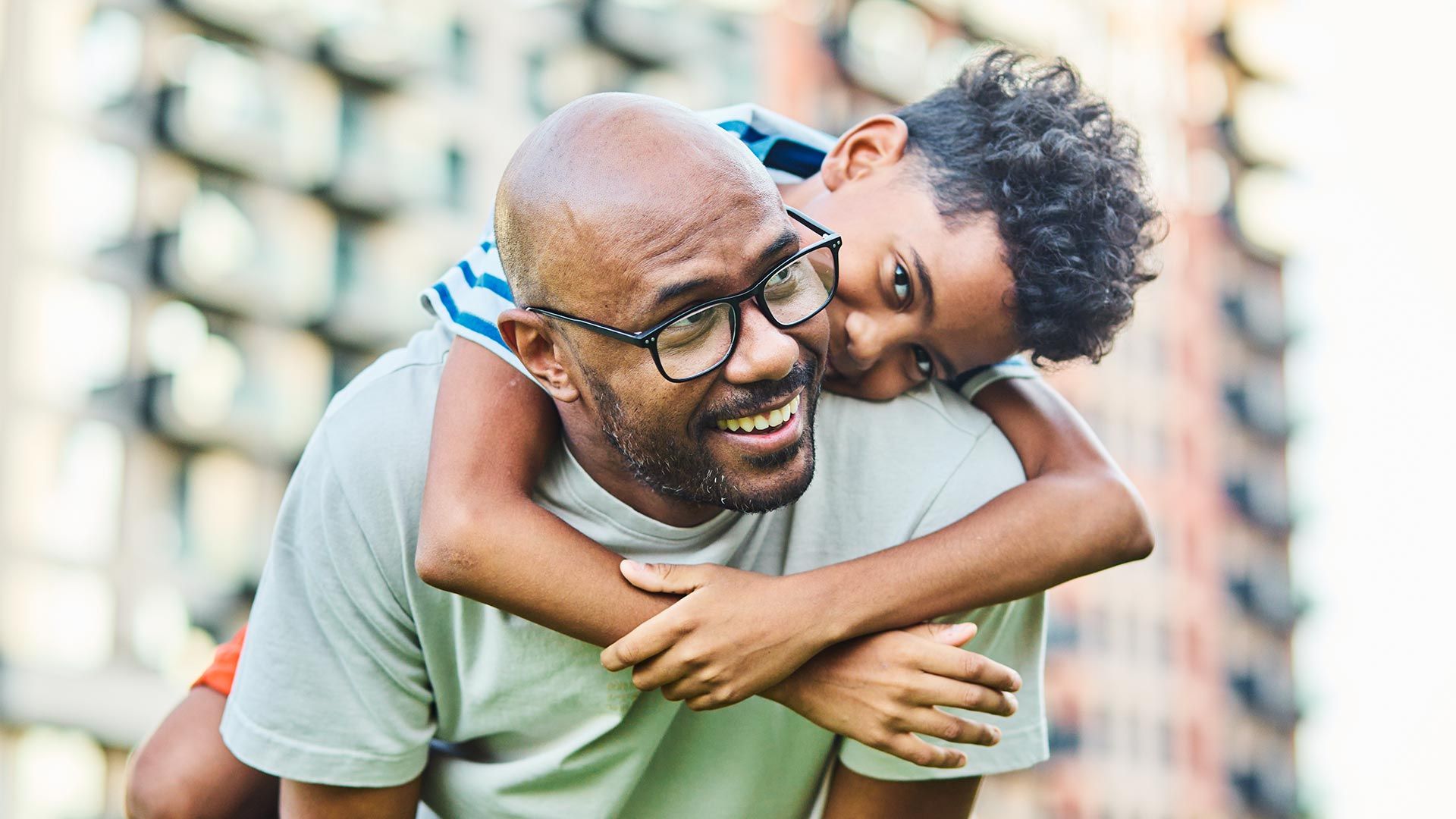 Father bends forward while carrying his son on his back outdoors