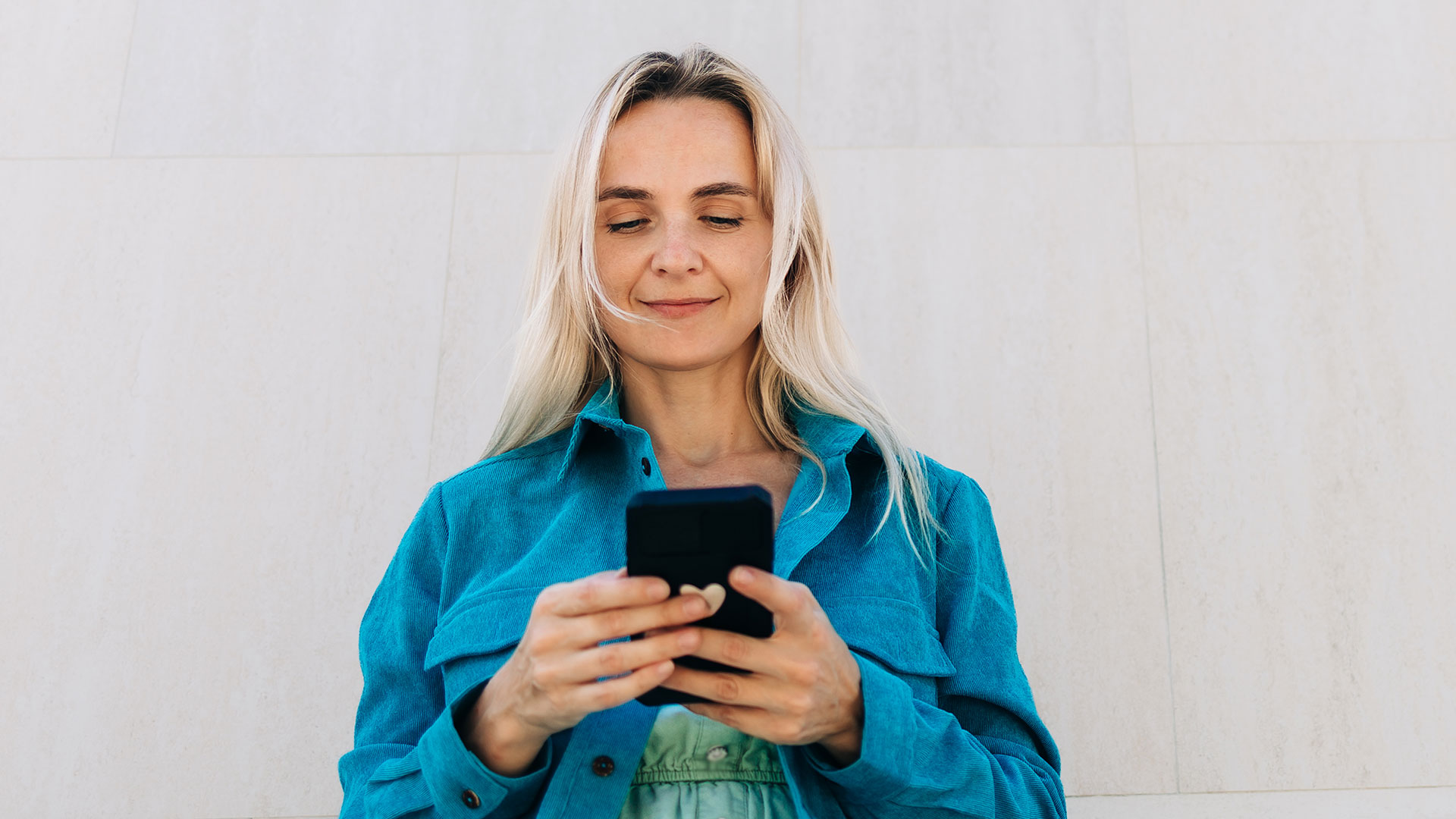 Woman in blue jacket looking at her phone