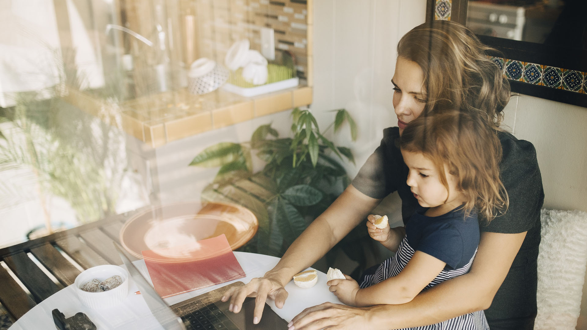 woman with daughter in her lap reviewing the diversity of benefits offered by her employer