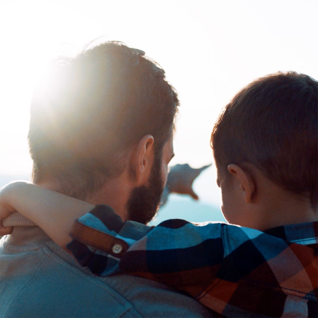 Man points to something in the distance while holding his son