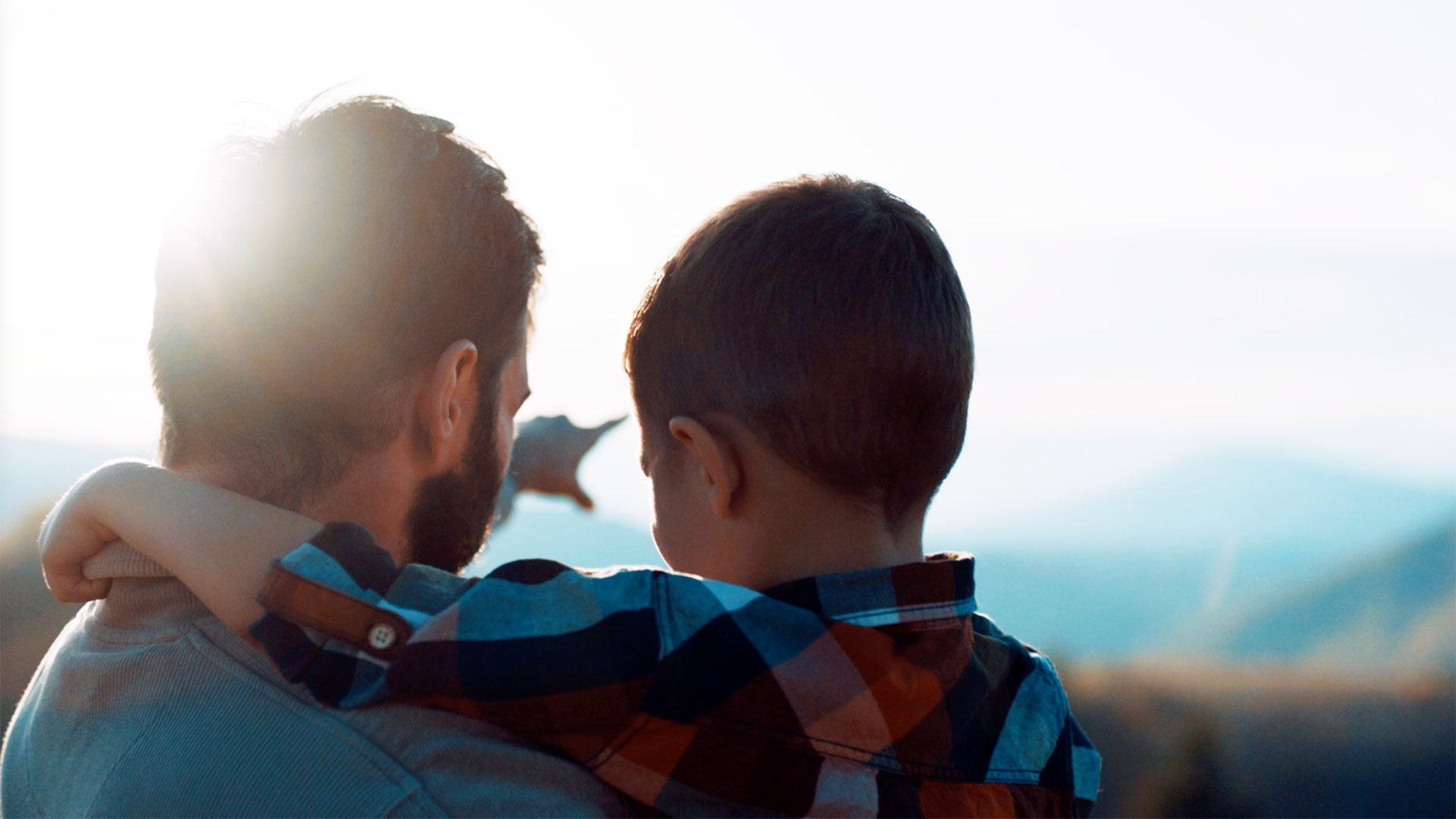 Man points to something in the distance while holding his son