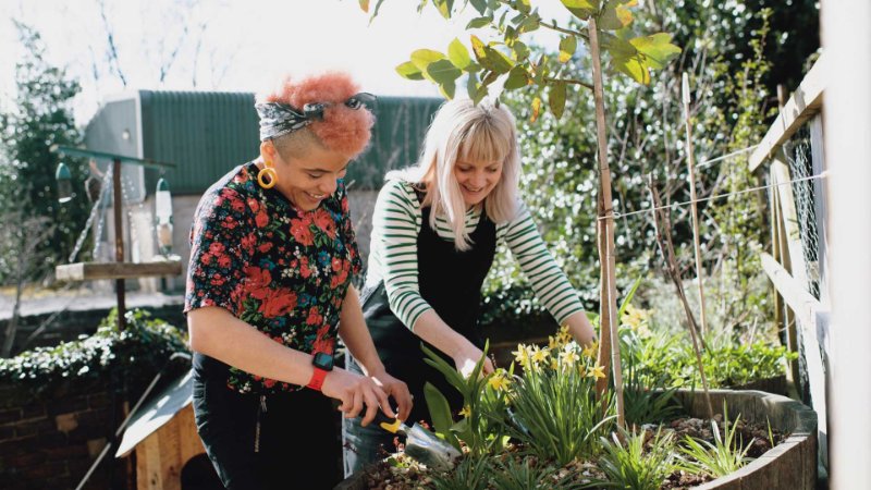 two women gardening while discussing employee wellbeing