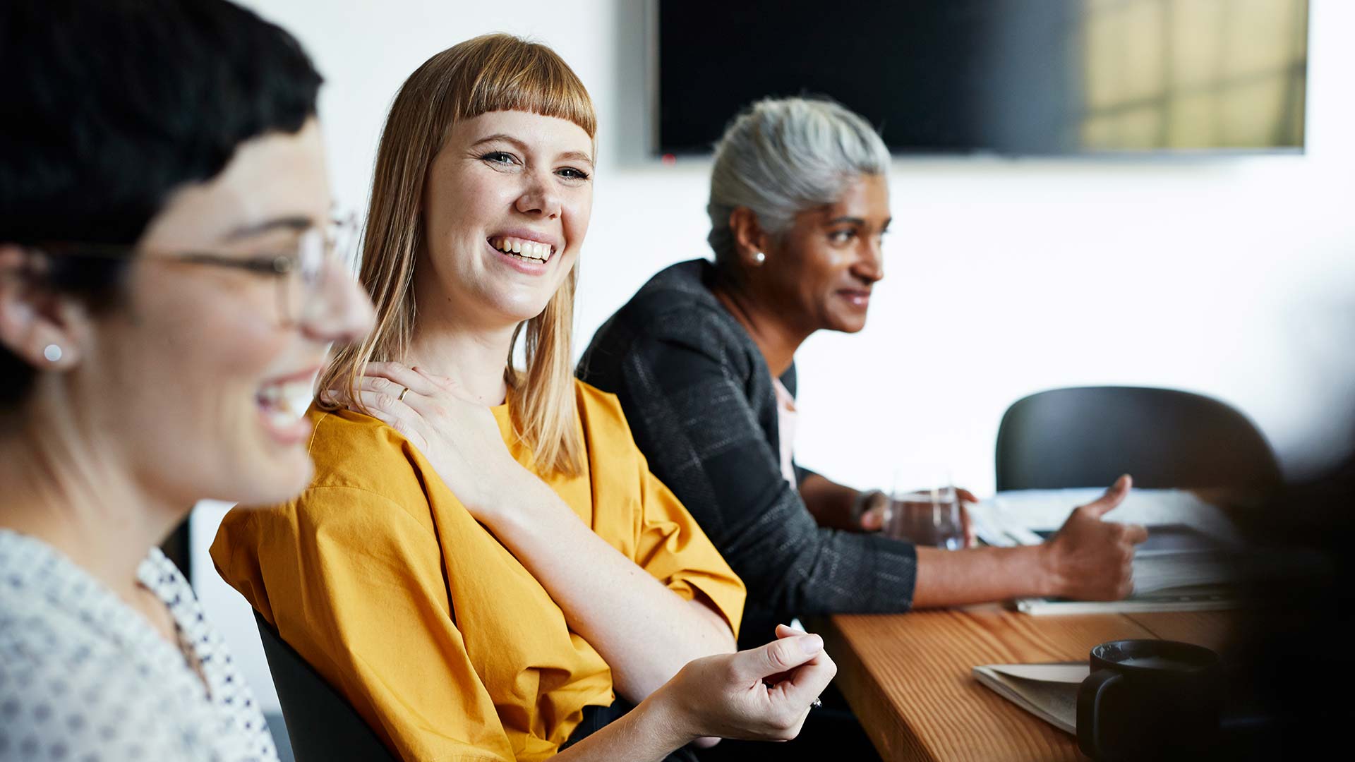 Office employees laugh together during a meeting